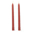 Two twisted red candles on a white background