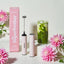 Pink milk frother with packaging and flowers on a light background