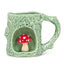 Green ceramic mug shaped like a tree with a red mushroom inside on a white background