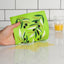 Green kitchen towel with leaf pattern held by a hand on a white countertop.