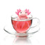 Pink axolotl-shaped tea infuser in a glass of tea on a white background