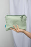 Green striped pouch held by a hand against a plain background