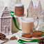 Gingerbread-themed setup with a mug of hot chocolate, cookies, and gingerbread houses.