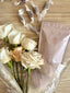 Bouquet of white and peach roses with a pink package on a textured surface