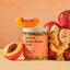 Jar of 'Ginger Peach Glow' tea blend with ginger root, peach slices, and a peach on a peach-colored background.