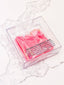 Pink candy in a clear box on a marble surface