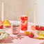 Strawberry Sencha Lemonade jar with a strawberry lemonade drink, strawberries, and lemon slices on a pink table.