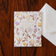 Floral birthday card with a white envelope on a wooden surface