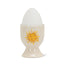 Ceramic egg cup with sun design holding a white egg on a white background