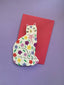 Card shaped like a cat with floral patterns on a red envelope against a purple background