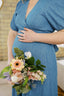 Person wearing a blue dress holding a bouquet of flowers indoors.