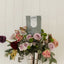 Bouquet of flowers in a silver vase with a bag of caramels on a white wooden background