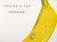 A minimalist art print featuring a textured yellow banana illustration on a white background, with the text 'YOU'RE A TOP BANANA' in a muted green handwritten font.