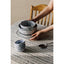 Set of black and white patterned ceramic bowls on a table with a person's hand reaching towards them.