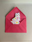 Red envelope with a cat-themed card inside on a beige background