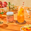 Ginger Peach Glow product with a glass of iced tea and peach slices on an orange surface.