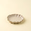 Ceramic dish with scalloped edge on a beige background