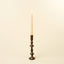 Tall candle with a decorative metal holder on a beige background