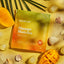 Lake & Oak Mango Matcha matcha latte mix package on a yellow background with mango slices and shells.