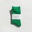 Green sock with a white label on a light gray background