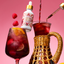 Red drink being poured into a glass with a bottle labeled 'Anará' and raspberries on a pink background.