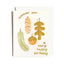 A white greeting card with gold foil text reading 'Wishing you a very happy birthday' and gold-accented autumn illustrations including a pinecone, acorn, and leaf, shown with a white envelope behind it on a light gray background.