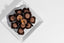 Chocolate candies in a white square dish on a light gray background