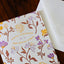 Greeting card with floral design and 'Happy Birthday to a Very Special Human' text on a wooden surface.