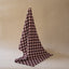 tea towel featuring a dark red and cream ikat-style geometric pattern, hanging from a thin cord against a solid beige background.