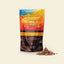 A stand-up pouch of GNAB Hot Chocolate Flakes in Salted Caramel flavor, displayed on a light cream background with a small pile of the chocolate flakes next to it.