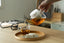Tea being poured from a glass teapot into a cup on a wooden tray with a blurred background.