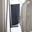 Black textured scarf and white shirt hanging on a rack against a neutral background
