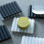 Yellow soap bar with 'S BOARD' branding on a textured gray surface