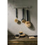 Set of cleaning brushes with black handles and natural bristles hanging on a wall hook against a textured wall.