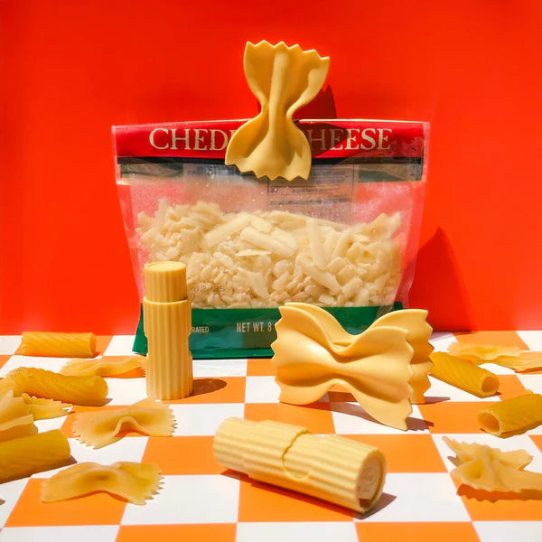 Packaged bow-tie pasta with a red label on a checkered tablecloth.