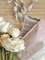 White roses, wrapped candies, and a pink packaging with text on a textured surface.