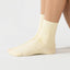 Beige sock worn by a person on a light gray background
