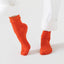 Orange socks worn with white pants on a light gray background