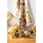 Two bee-themed crochet coasters on a wooden surface with a floral-patterned towel in the background.