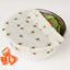 Beeswax wrap with bee and honeycomb pattern on a metal plate with vegetables