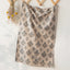 Floral patterned fabric hanging on a wooden rack against a white wall.