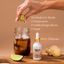 Shroom Soda bottle with a hand adding a lime wedge to a glass of iced liquid on a wooden surface.