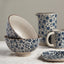 Ceramic bowls, pitcher, and mug with blue floral pattern on a neutral background