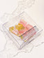 Clear box with watermelon and banana-flavored gummy candy on a marble surface