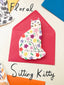 Decorative card with a floral-patterned sitting kitty design on a pink envelope.