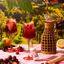 Two glasses of red sangria with fruit on a table outdoors, with a person pouring liquid into a pitcher.