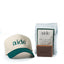 Beige cap with teal brim and 'aide' branding, next to a bar of soap and packaging on a white background