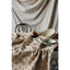 Table setting with ceramic bowls and a teapot on a patterned cloth against a draped fabric background