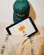 Green cap and tablet on beige fabric with 'aide' branding