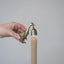 Brass duck-shaped candle holder with a bell on a lit candle against a gray background